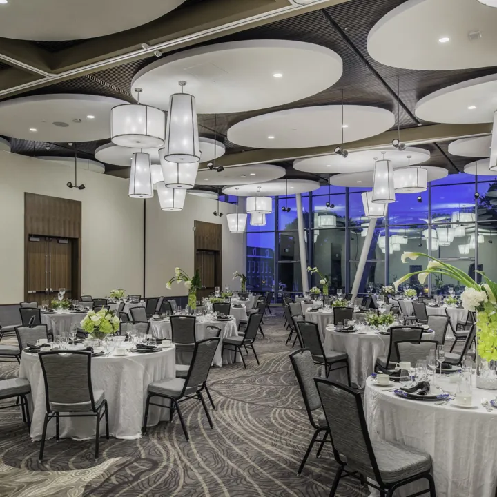 Ballroom set up for an event with tables that have Easter lily centerpieces
